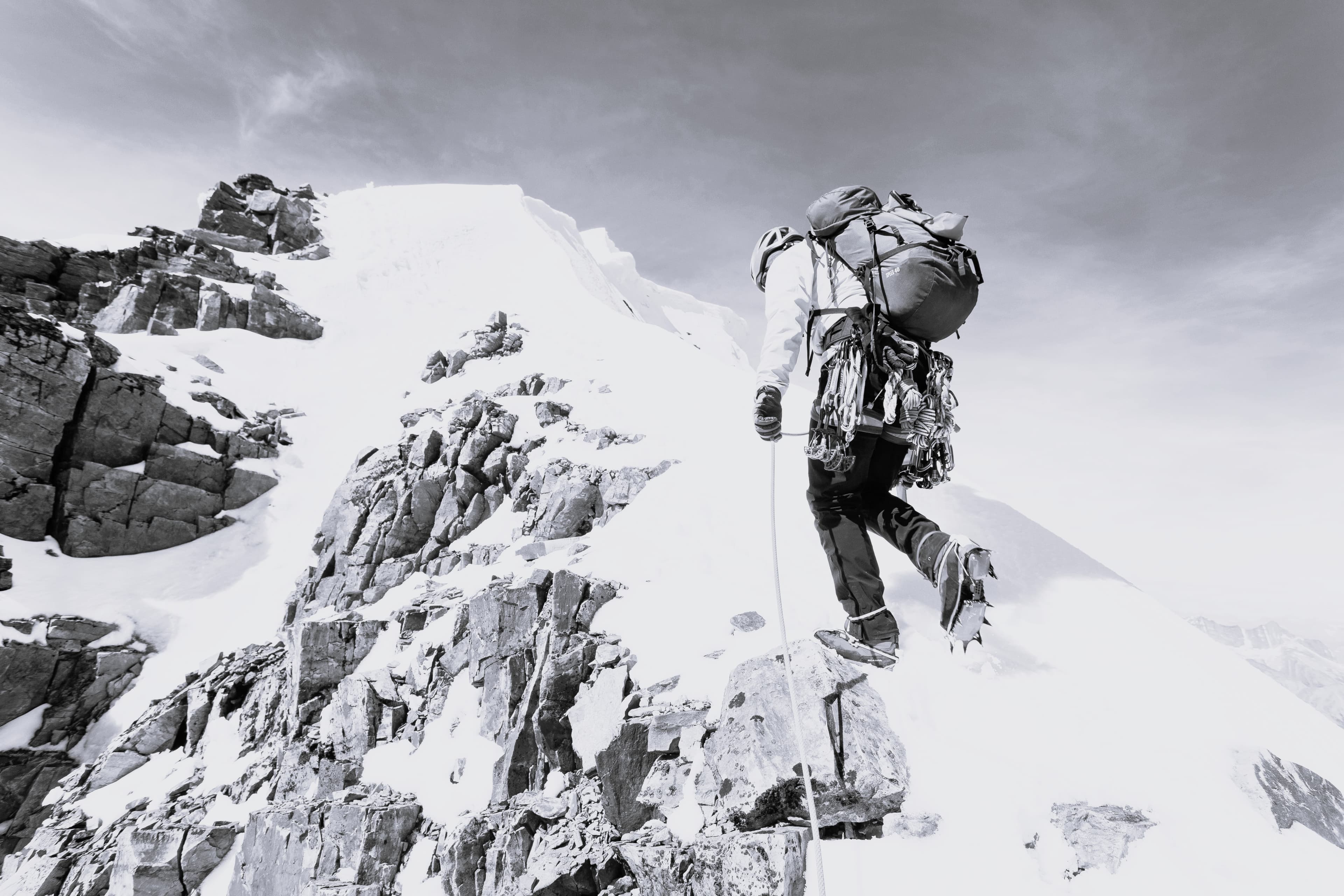 A single climber stepping onto an exposed summit ridge